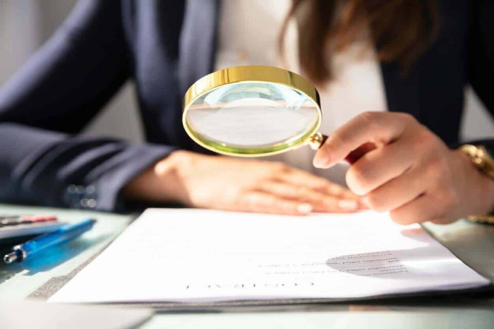 Businesswoman Looking At Contract Form Through Magnifying Glass