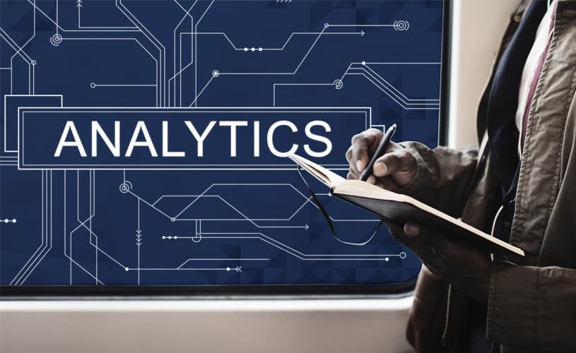 The word Analytics with a man taking notes