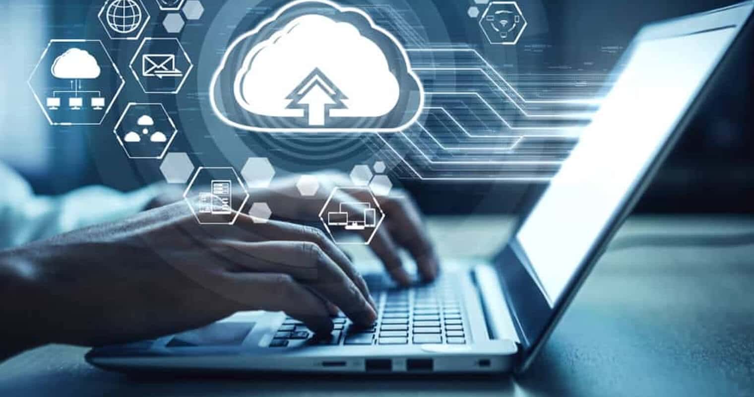 Une personne se consacrant à la gestion des données dans le nuage, travaillant sur un ordinateur portable avec un graphique de nuage en arrière-plan.