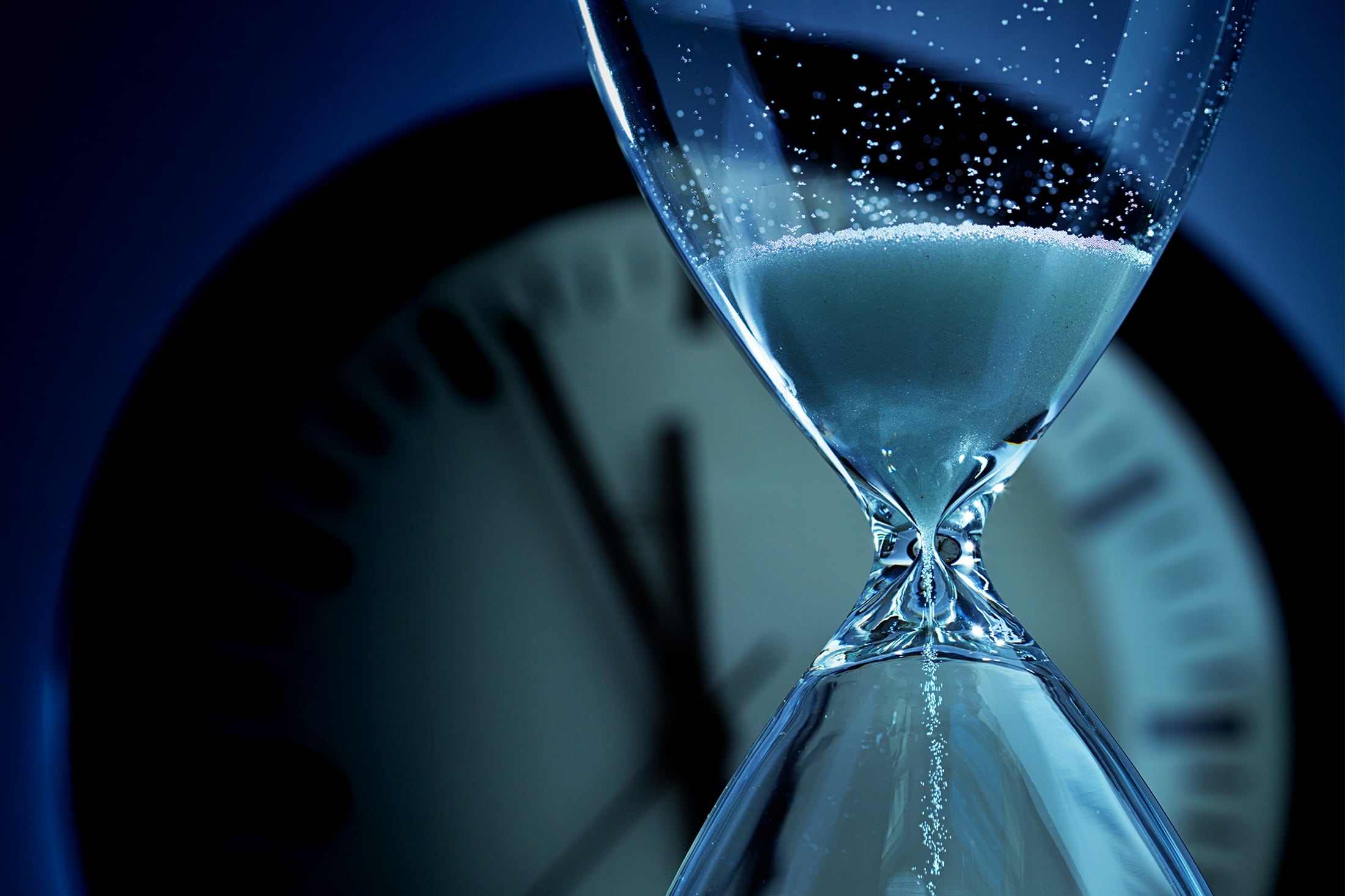 hourglass with a clock behind it